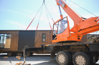 Crane operator lifting prefabricated modular house onto truck, showcasing efficiency in modern construction and housing transportation