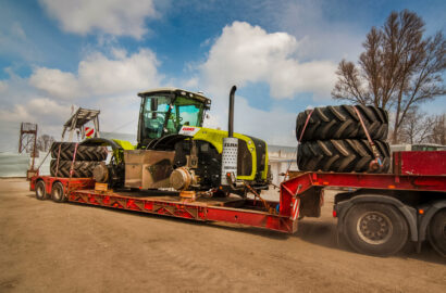 TERNOPIL REGION, UKRAINE - MARCH 29, 2019: A truck on a trailer transports a dismantled tractor to a repair base in preparation for the agricultural work season